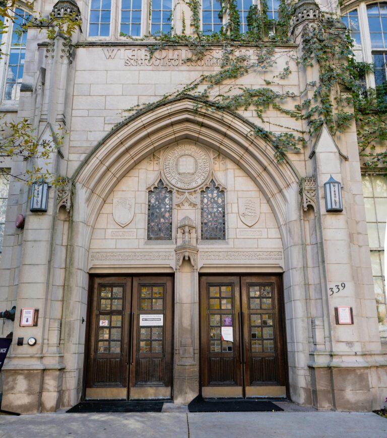 Gothic stone facade of university entrance with intricate designs and ivy in Chicago.